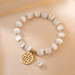 Detailed macro view of white opal beads and gold Fu character charm on a beaded bracelet