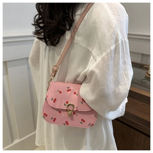Detail of pink saddle bag with cherry print and golden buckle worn cross-body