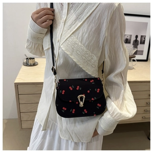 Floral saddle crossbody bag with cherry print and metal buckle shown on model