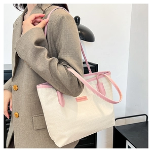 Model wearing large contrast color tote bag with geometric embossing and pink straps