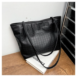 Detail of black tote bag with star pattern embossing and fashion metal logo plate