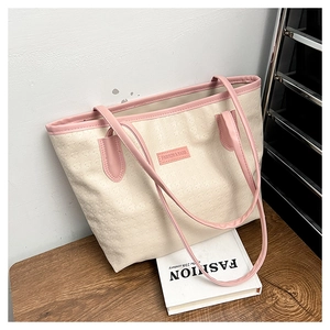 Detail of star-embossed cream tote bag with pink contrast stitching and brand label