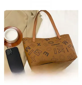 Detailed view of the brown leather tote bag with stylish black letter patterns on surface