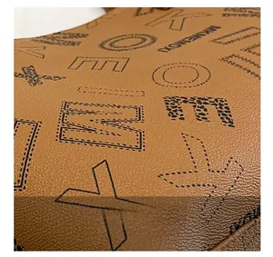 Detail of brown lychee grain leather with stylized printed letters and leopard pattern