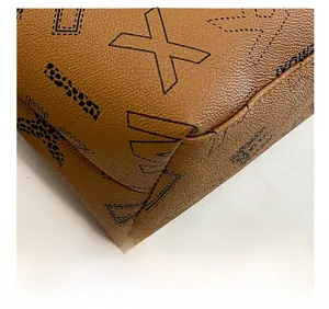 Detail of brown leather tote bag showing lychee grain texture and stitching