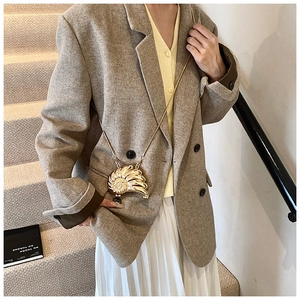 Detail of a shiny gold shell-shaped mini bag with a fine chain strap for women