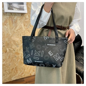 Detail of black leather tote bag with white letter print and adjustable shoulder straps