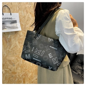 Detailed side view of black tote bag with white letter prints and dual shoulder straps