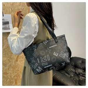 Detail of black leather tote bag featuring white letter print and slim shoulder straps