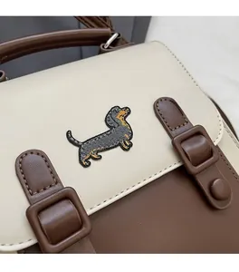 Détail de la broderie de teckel et boucle en cuir sur le sac à dos vintage bicolore