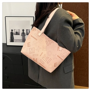 Detail of pink PU leather tote bag with geometric letter pattern worn over the shoulder