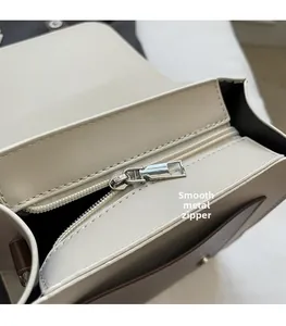 Détail de la fermeture éclair en métal argenté sur un sac à dos crème en similicuir texturé