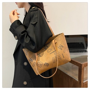 Brown vintage tote bag with black letter print worn by a model in a black wool coat