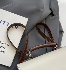 Détail d'un sac à dos en cuir blanc avec bretelles marron réglables et boucles en métal