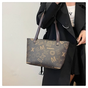 Close-up of brown patterned tote bag on model wearing a stylish black wool coat