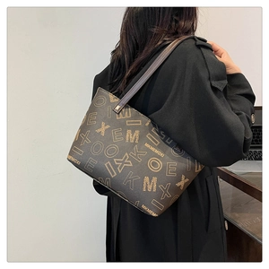 Brown monogram tote bag styled with a black trench coat shown from a side view