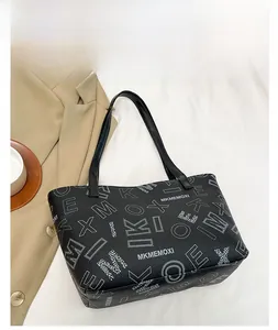 Flat lay of black leather tote bag with white letter print and stylish beige suit decor