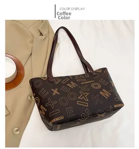 Top view of large brown tote bag with logo print next to a blazer and coffee cup