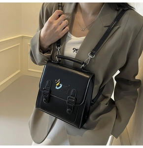 Detail of a chic black faux leather backpack with colorful cartoon dog pattern and buckles