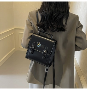 Detail of cute puppy embroidery on black glossy PU leather backpack for women