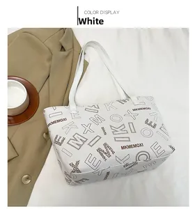 Close-up of a white faux leather tote bag featuring letter print and brand lettering