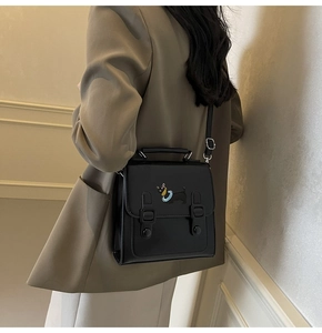 Detail of black matte leather handbag with cute puppy embroidery on a brown blazer