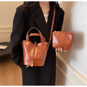Retro brown bucket bag set with top handle and crossbody strap on black coat