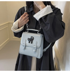 Detail of light blue faux leather backpack featuring a black cat embroidery patch