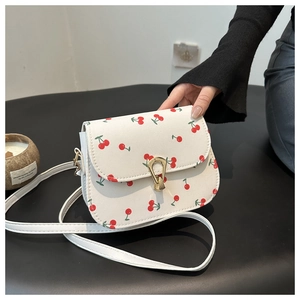 White faux leather saddle bag with red cherry prints and golden swivel lock closure