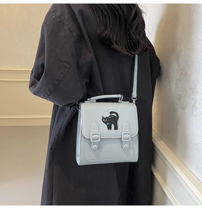 Detailed back view of a light blue puppy pattern backpack on a model in a black coat