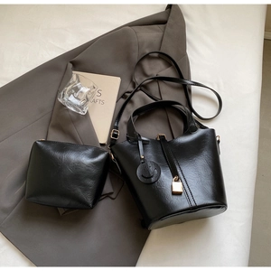 Détail du sac seau noir en cuir avec breloque sourire et petite pochette assortie