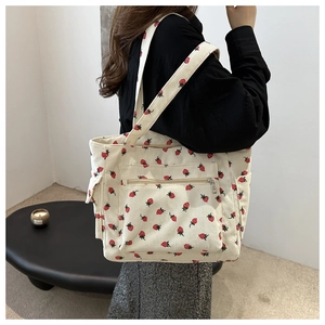 Detail of strawberry print corduroy tote bag showing side pocket and zippered front pouch