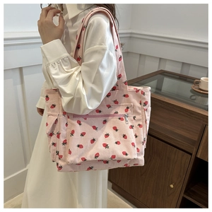 Pink corduroy tote bag with red strawberry print and front zipper pocket on a model