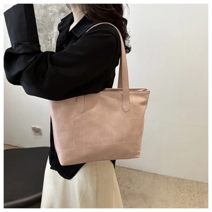 Detailed view of pale pink tote bag featuring geometric quilted stitching and long shoulder straps