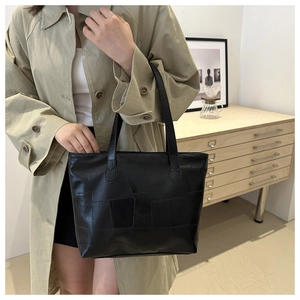 Detailed view of black patchwork tote bag worn on shoulder for daily commute style