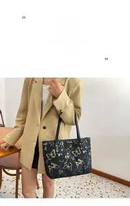 Detail of black tote bag with gold butterfly pattern and elegant shoulder strap
