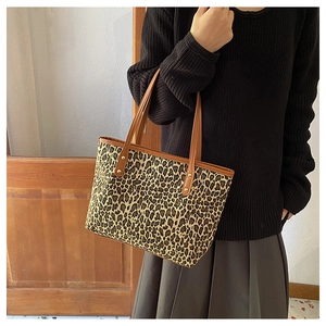 Detail of leopard print tote bag featuring brown leather trim and metal rivets on shoulder strap