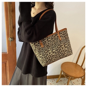 Chic leopard print tote bag with brown leather straps worn by model in warm indoor setting
