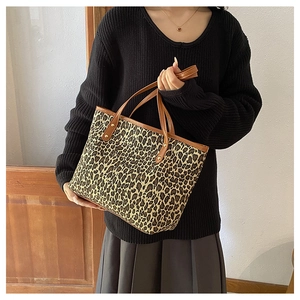 Detailed view of leopard print tote bag with brown leather handles and golden rivets