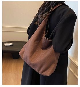 Detailed side view of the spacious dark brown suede tote bag worn on shoulder