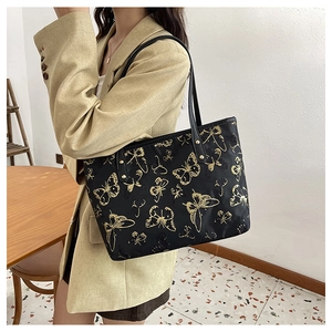 Detail of butterfly embroidery on black tote bag with premium gold metallic hardware