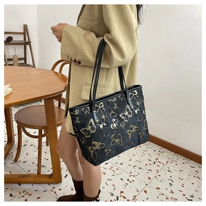 Macro detail of high-capacity tote bag featuring gold butterfly patterns and nylon texture