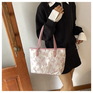 Detail of butterfly jacquard fabric and pink leather handles with gold studs on tote bag