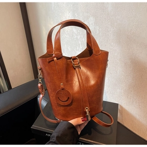 Sac seau marron vintage avec breloque smiley et poignées dans un cadre élégant