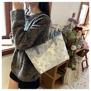 Close-up of butterfly jacquard tote bag with blue handles and rivet details