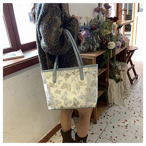 Detailed embroidery of gold and silver butterflies on a beige jacquard tote bag
