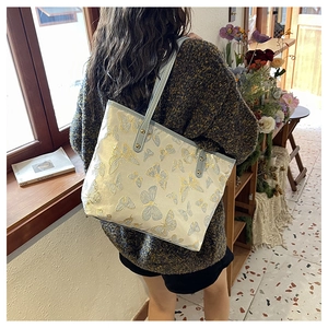 Detail of elegant butterfly embroidery and light blue strap on chic off-white tote bag