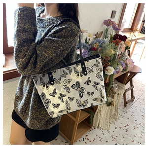 Detailed shoulder view of a cream jacquard tote bag with elegant butterfly patterns