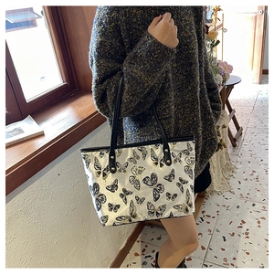 Detailed close-up of butterfly embroidery on a chic jacquard fabric tote bag with leather strap