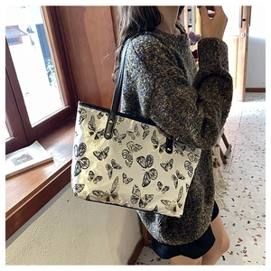 Detailed close-up of butterfly jacquard embroidery on large tote bag with leather straps